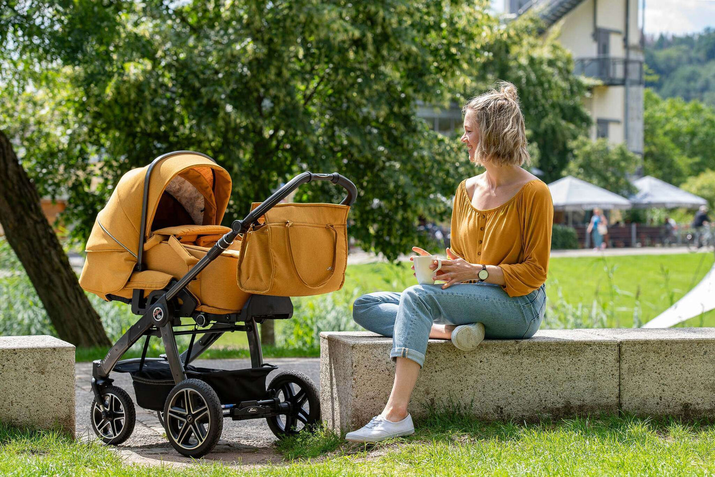 Frau sitzt im Park mit Ihrem Kinderwagen