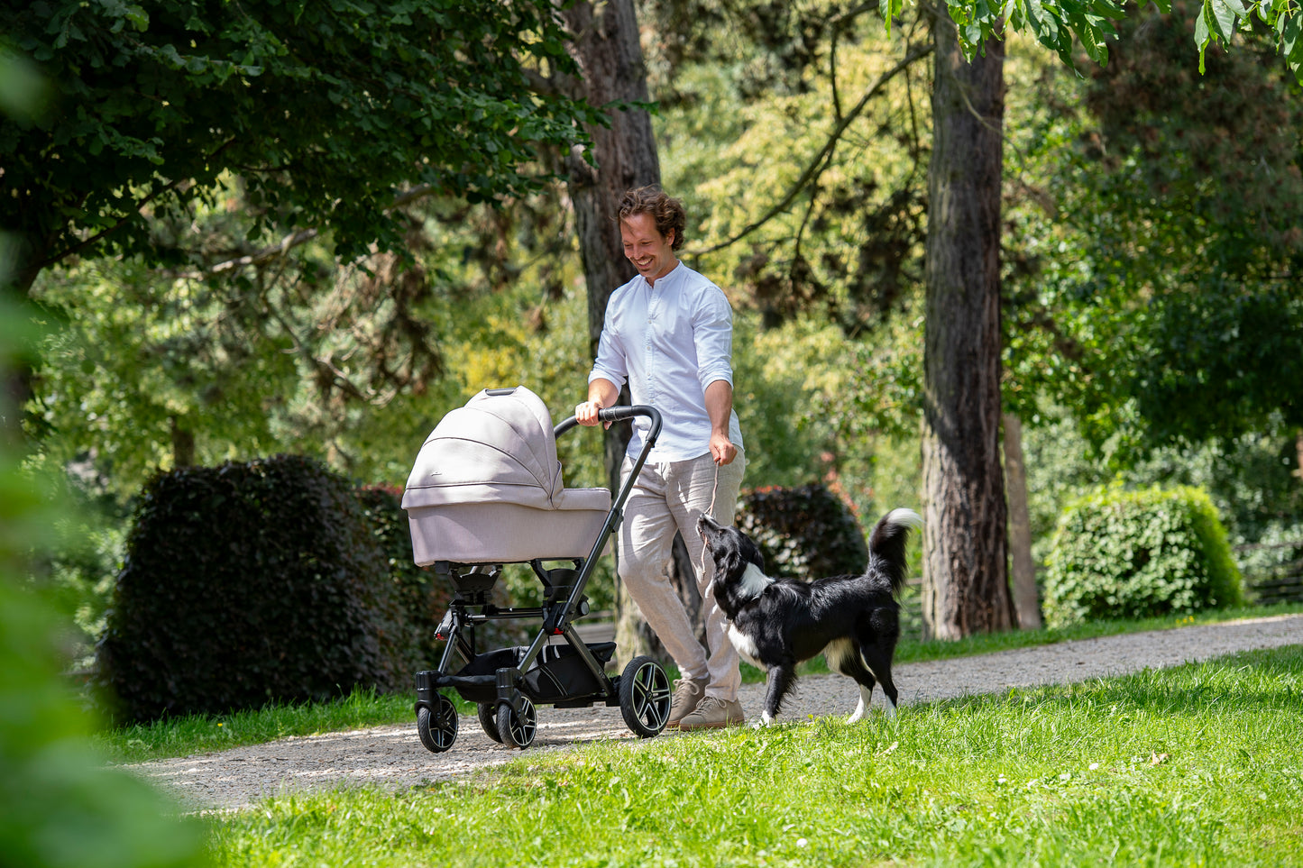 Vater mit Hund und Kinderwagen im Park